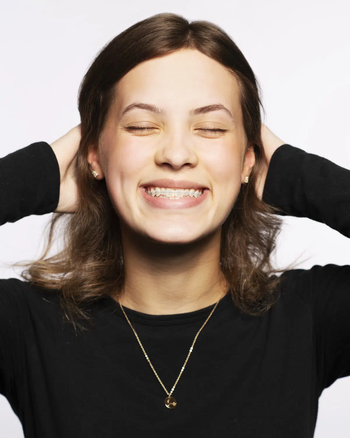 A woman smiling with her hands behind her head.