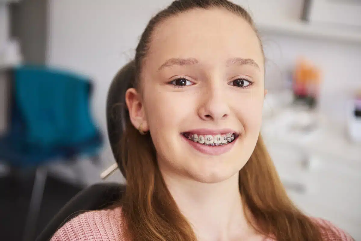 A young girl with braces smiles for the camera.